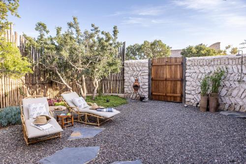un patio trasero con 2 sillas y una pared de piedra en The Moonlight Yurt, en Essaouira