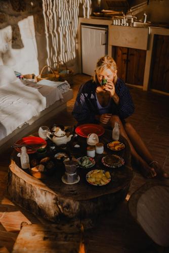 a woman sitting on the floor with a table full of food at The Moonlight Yurt in Essaouira