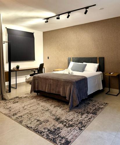 a bedroom with a large bed and a large screen at Perfect Campolim loft in Sorocaba