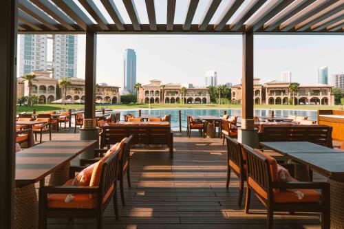a restaurant with tables and chairs and a pool at Royal Saray Resort in Manama