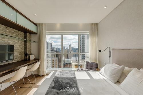 a bedroom with a large bed and a large window at Estúdio em Cond c/ Piscina e Academia NWC1510 in Curitiba