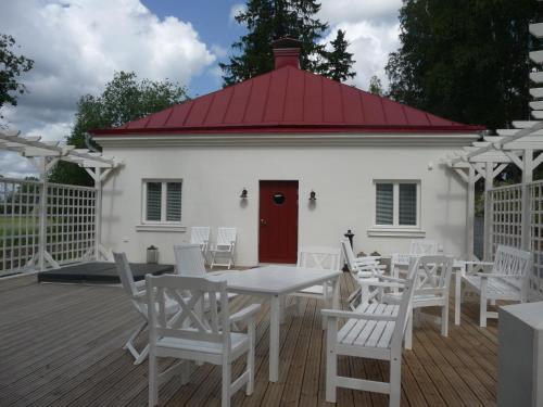 a white building with a red roof and white tables and chairs at Vaihmalan Hovi in Lempäälä