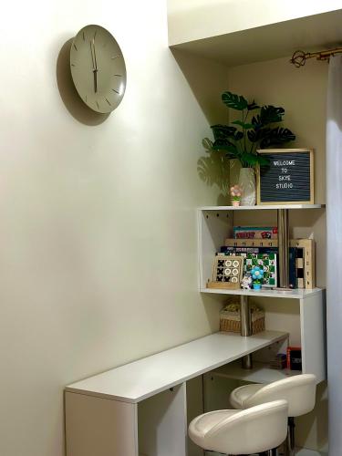 a clock on the wall next to a white desk at Tagaytay Condo - Skye Studio in Kaybagal