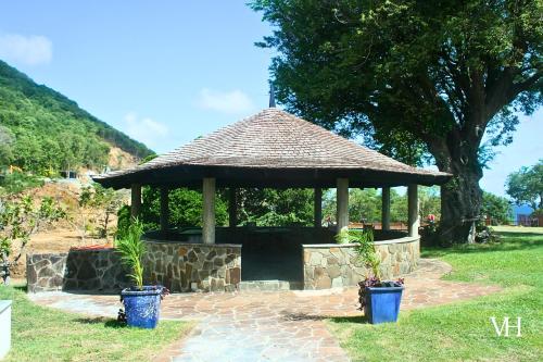 a gazebo with a straw roof and two potted plants at The Triplex at Villa Horizon - Three Private Suites in Rodney Bay Village