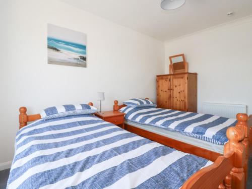 two beds in a bedroom with white walls at Tregundy Farmhouse in Perranporth