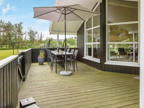 a wooden deck with a table and an umbrella at 6 person holiday home in Jerup-By Traum in Jerup