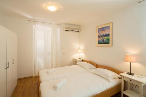 a white bedroom with a bed and a window at Central Apartment in Dubrovnik