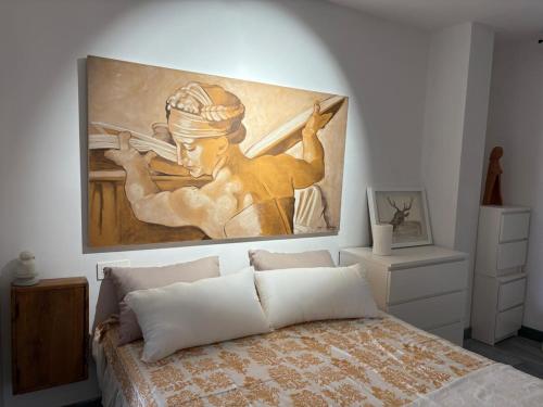 a painting hangs above a bed in a bedroom at Estudi d art i natura in Villahermosa del Río