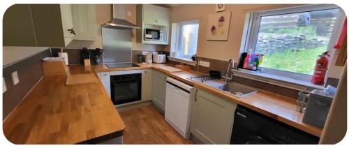 a kitchen with a wooden counter top and a window at Ghillies Cottage, Loch Ness in Milton