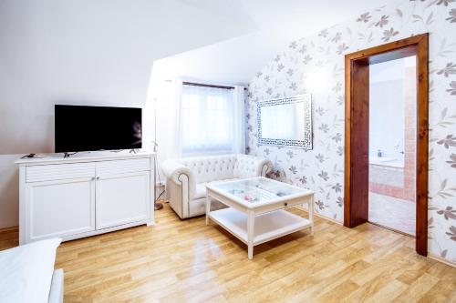 a living room with a white couch and a tv at Penzion Tillerova vila in Lázně Bohdaneč