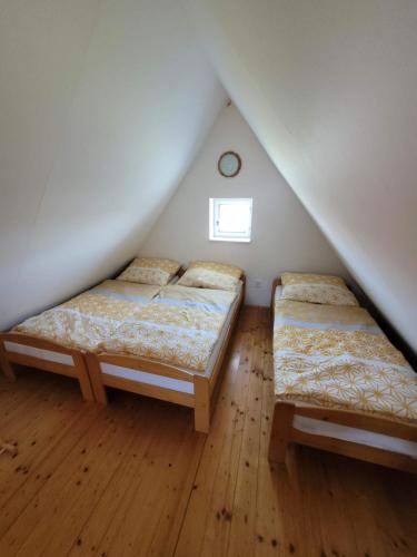 two beds in a attic bedroom with a window at Kolo a ryby Bulhary in Břeclav