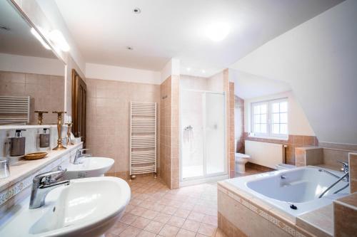 a large bathroom with two sinks and a tub at Penzion Tillerova vila in Lázně Bohdaneč