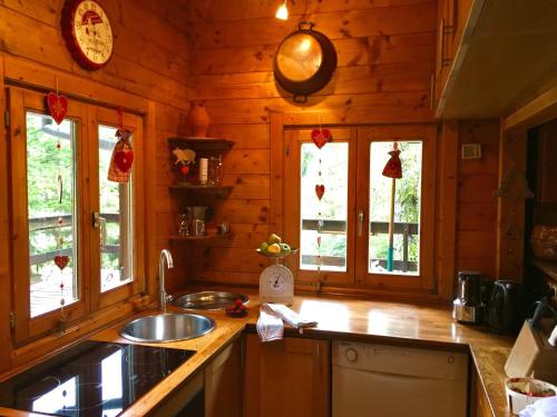 a kitchen with a sink and windows in a log cabin at Chalet near Bitche with Private Sauna in Bousseviller
