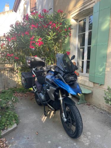 a blue motorcycle parked next to a building with flowers at Les volets verts in Saint-Laurent-de-la-Cabrerisse