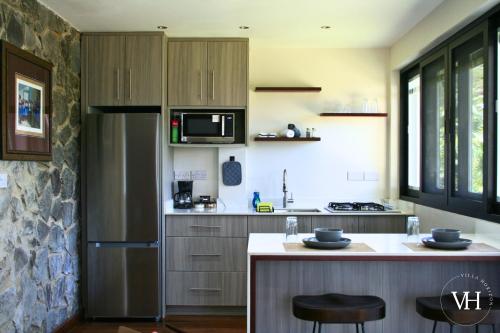 Una cocina con refrigerador y una encimera con taburetes. en The Bougainvillea Studio at Villa Horizon, en Rodney Bay Village