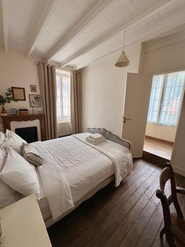 a bedroom with a large white bed and two windows at La Belle Vienne in Exideuil
