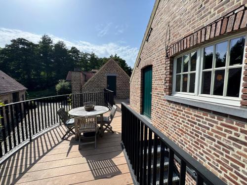 a patio with a table and chairs on a balcony at De Oude Molen in As