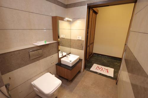 a bathroom with a toilet and a sink and a mirror at Nexstay Hotel Calicut Gate in Kozhikode