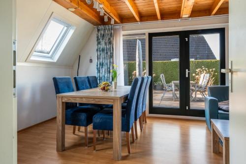 a dining room with a wooden table and blue chairs at Lovely bungalow with woodburner and airco in Zwiggelte