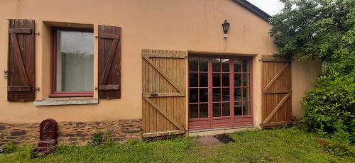 a house with a red door and windows at Cottage près de Rennes in Le Rheu