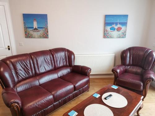 a living room with a leather couch and two chairs at Deja Blue in Sutton on Sea