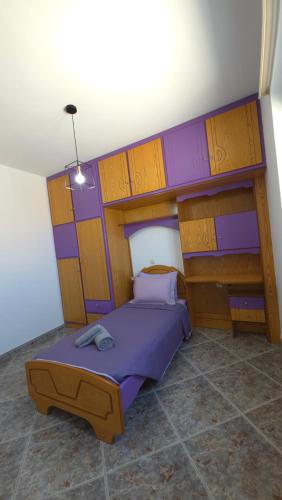 a bedroom with a purple bed with wooden shelves at HOME sweet HOME in Kefalos