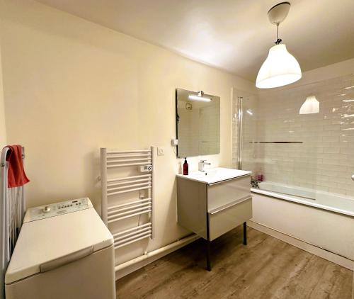 a white bathroom with a sink and a mirror at Eugène - Elégance & Confort in Reims