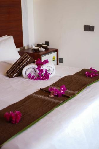 Una cama con toallas y flores púrpuras. en Valley Palm Seaview, en Guraidhoo