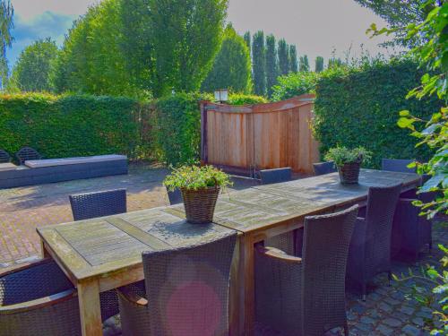a wooden table and chairs in a backyard at Holiday Home in Alphen near Het Zand Beach in Alphen