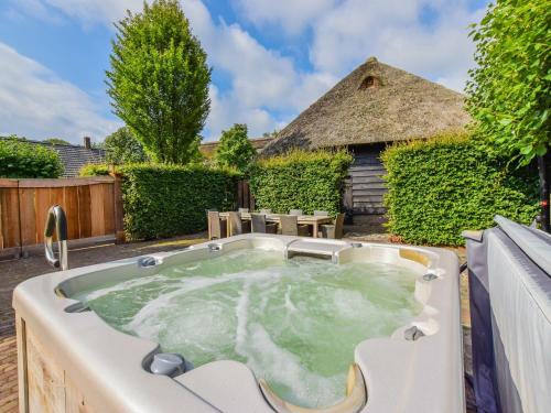 a hot tub in a backyard with a thatch roof at Holiday Home in Alphen near Het Zand Beach in Alphen