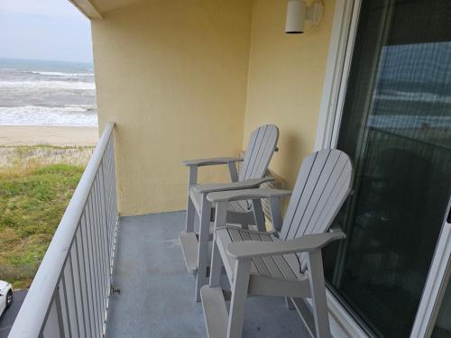 two chairs sitting on a porch looking out at the ocean at Surf Side Hotel in Nags Head