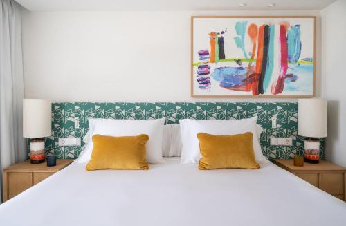 a bedroom with a large white bed with yellow pillows at Kimpton Los Monteros Marbella by IHG in Marbella