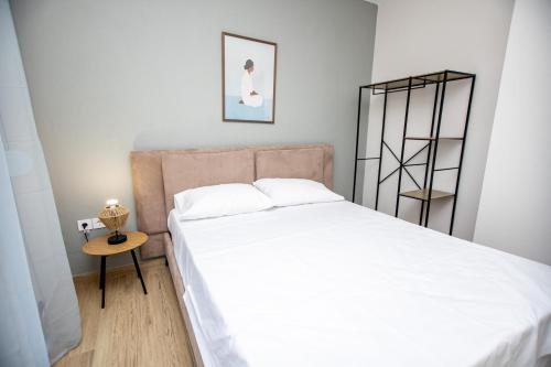 1 dormitorio con cama blanca y mesa auxiliar en Elea Home, en Nea Vrasna