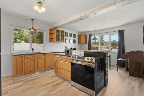 a kitchen with wooden cabinets and a black stove top oven at The Coal Stone throw away from Red Deer River 2BR House in Drumheller