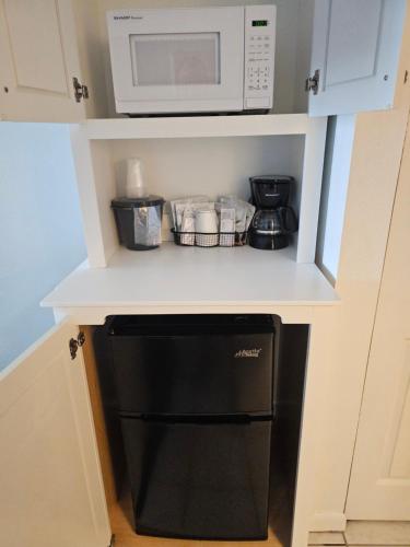 a small kitchen with a microwave and a black dishwasher at Surf Side Hotel in Nags Head