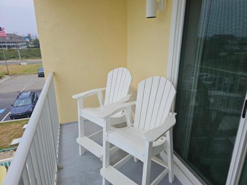 two white rocking chairs sitting on a porch at Surf Side Hotel in Nags Head