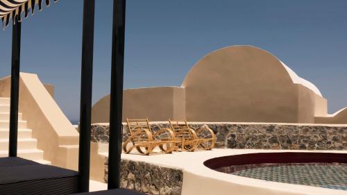 a group of chairs sitting on a ledge next to a pool at Neema Maison Finikia Santorini in Oia