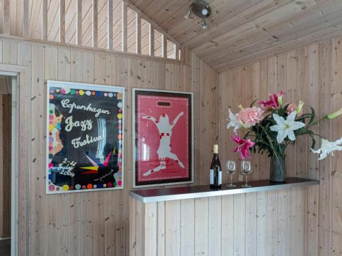a wall with two posters and a shelf with a vase of flowers at Luxury Retreat with Pool - By Traum Ferienwohnungen in Tisvildeleje