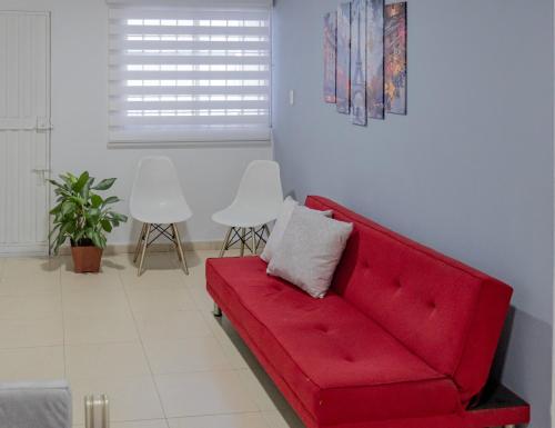 a red couch in a living room with two white chairs at Apartamentos La Ceiba in Valledupar