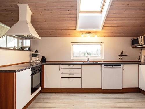 a large kitchen with white cabinets and a window at 14 person holiday home in Højslev in Sundstrup