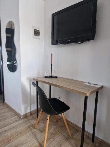 a desk with a chair and a television on a wall at Zen in Talmesch