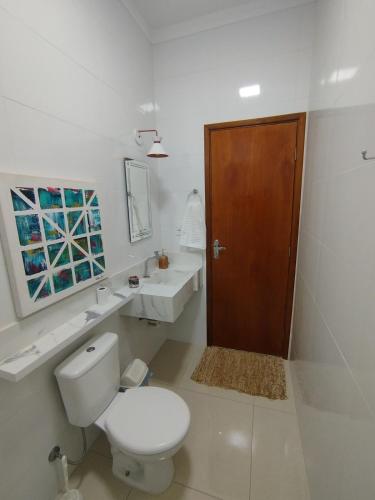 a white bathroom with a toilet and a sink at Apê aconchegante in Franca