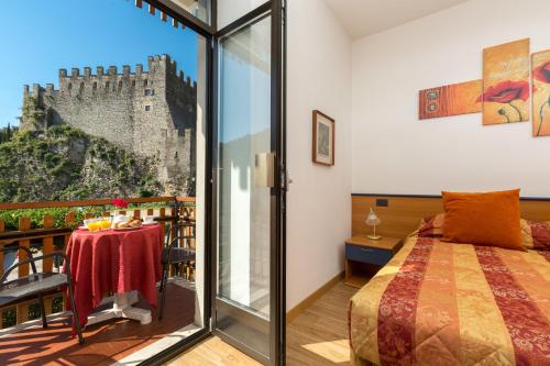 ein Schlafzimmer mit einem Bett und einen Balkon mit einem Schloss in der Unterkunft Hotel Antica Croce - Gardaslowemotion in Tenno