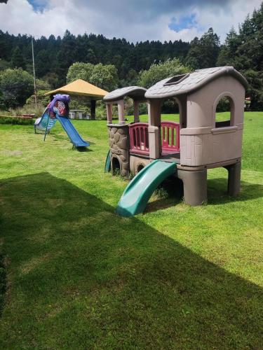 two children playing on a playground with a train at Palapas los Axolotes, Valle del Potrero, la Marquesa in San Pedro Atlapulco