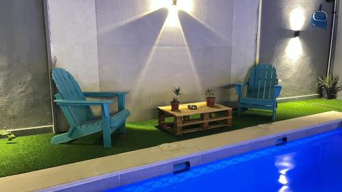 two chairs and a table next to a swimming pool at T Cozy Chalet in Ash Shāghūr