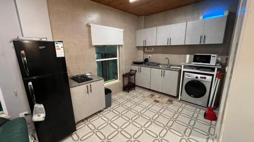a kitchen with a black refrigerator and a washer at T Cozy Chalet in Ash Shāghūr
