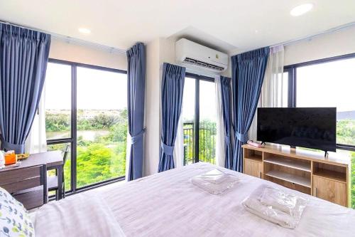 a bedroom with a bed and a tv and windows at Arunsakhon luxury condo in Ban Khok Kham