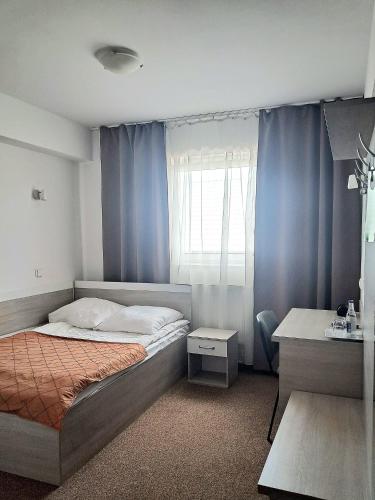 a bedroom with a bed and a window with blue curtains at Hotel Sezam Kraczkowa Smart Lock in Kraczkowa