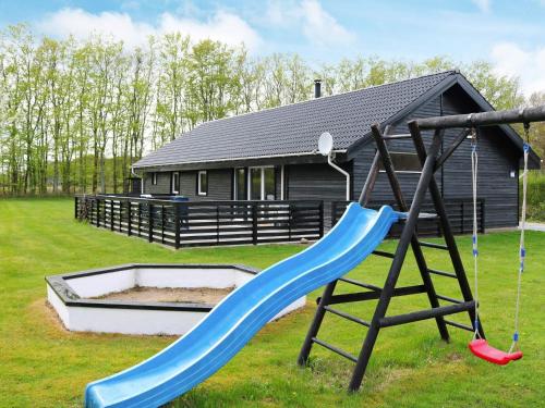 a playground with a slide in front of a house at 4 star holiday home in Storvorde in Storvorde