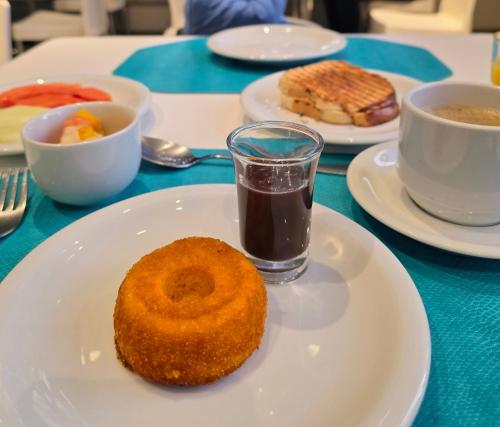 Un plato con una dona sobre una mesa con tazas de café. en Quarto 5 estrelas no Comfort Suites!, en Brasilia
